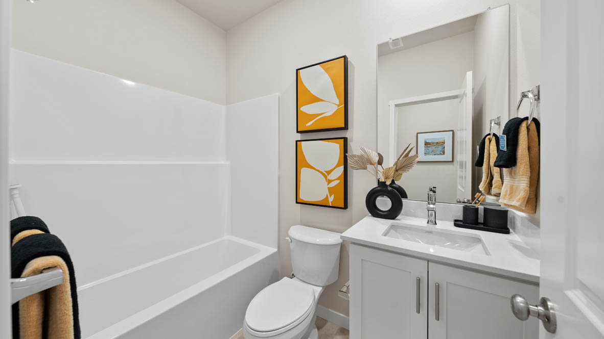 Stevens Ranch bathroom with white walls, quartz countertops, toilet, paintings, white cabinets, white tub
