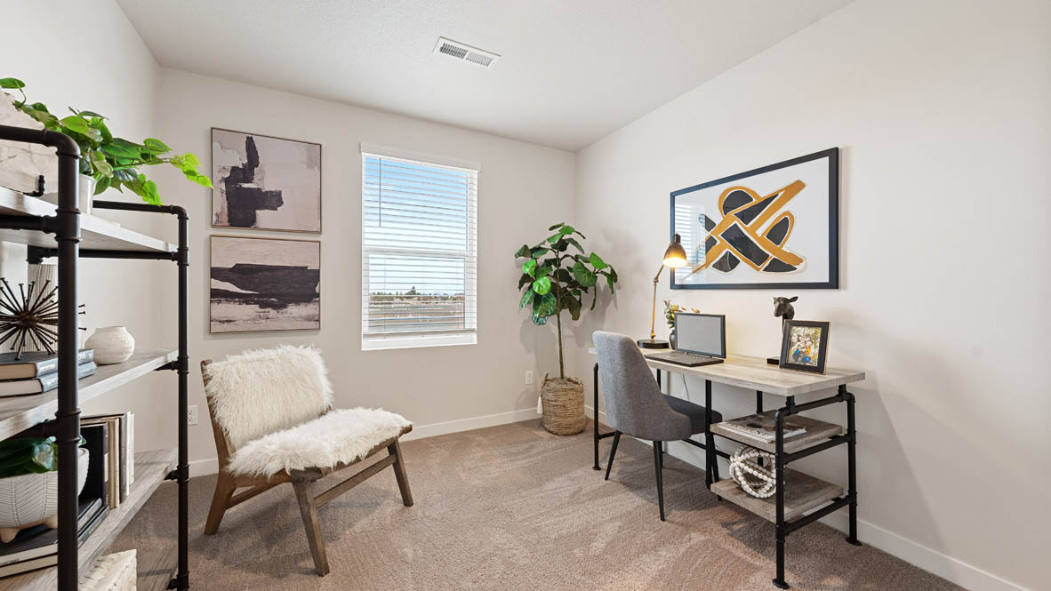 Stevens Ranch Den with chair, black shelving, working table, plants, and painting