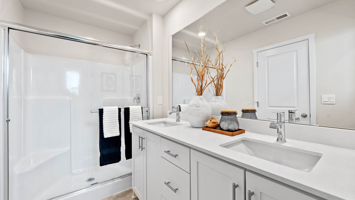 Stevens Ranch primary bathroom with white quartz countertops, mirror, white cabinets, white tub