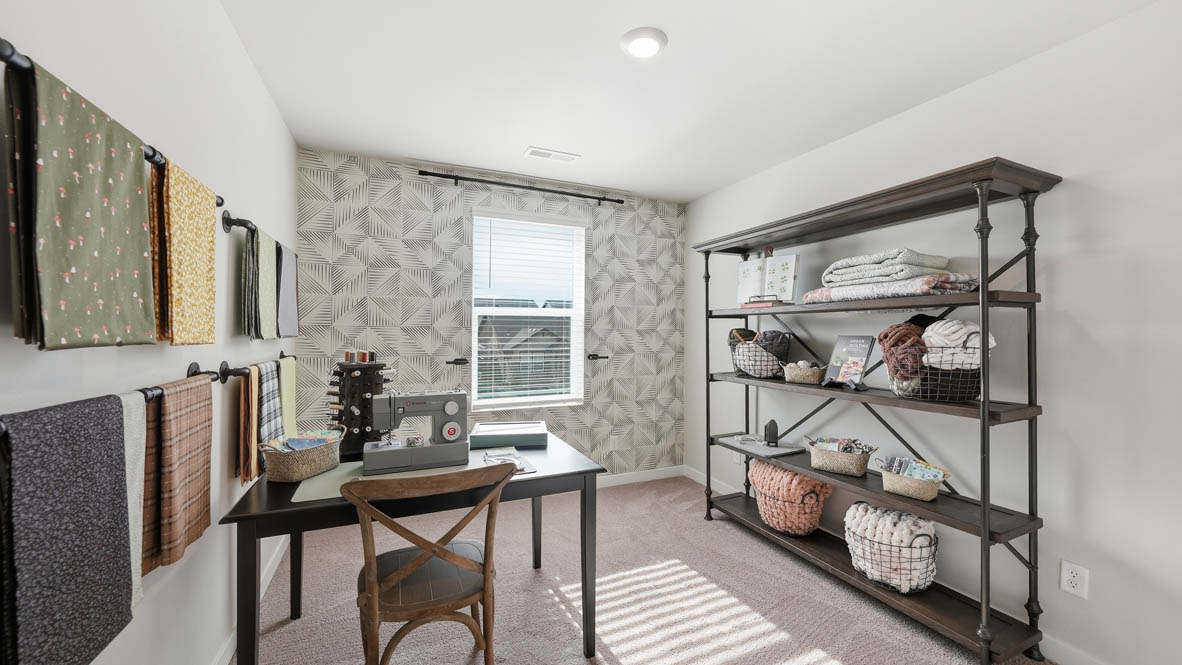 Stevens Ranch bedroom mock office with a desk, hung up shelves, a couch, chair, and a painting
