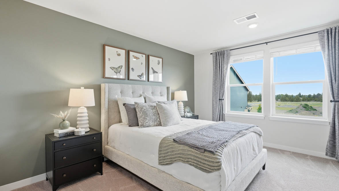 Stevens Ranch primary bedroom with painted accent wall and carpeting and bed with two side tables