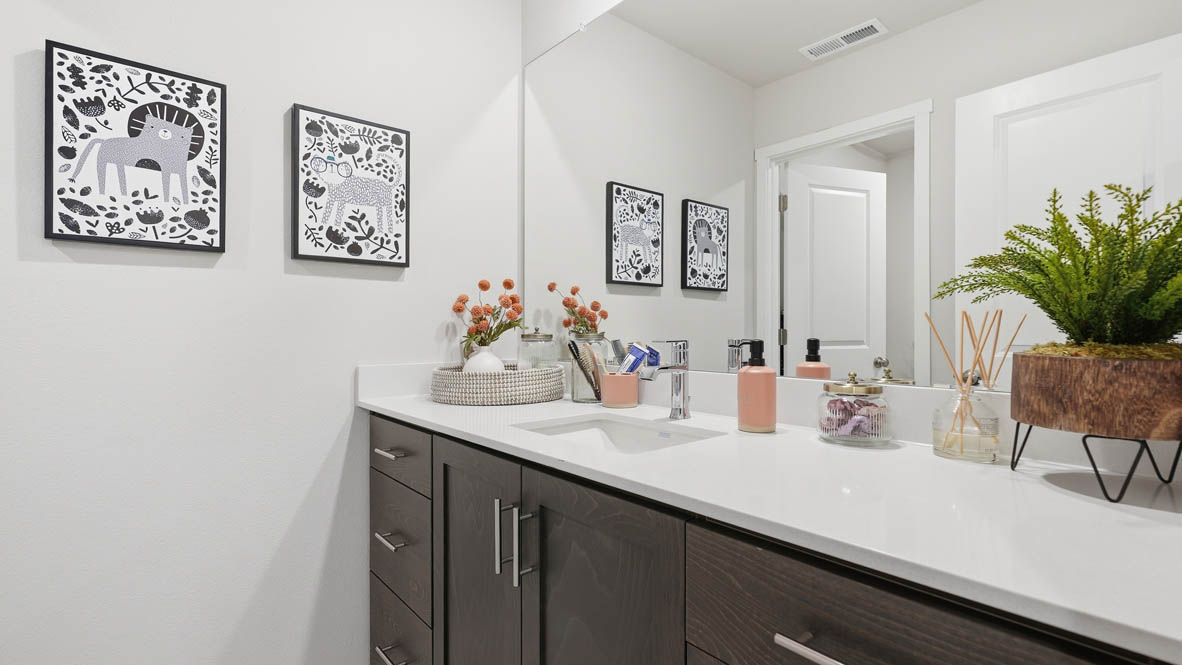 Stevens Ranch secondary bathroom with vanity with shaker style dark stained cabinets and white quarts countertops with toilet closet and tub shower