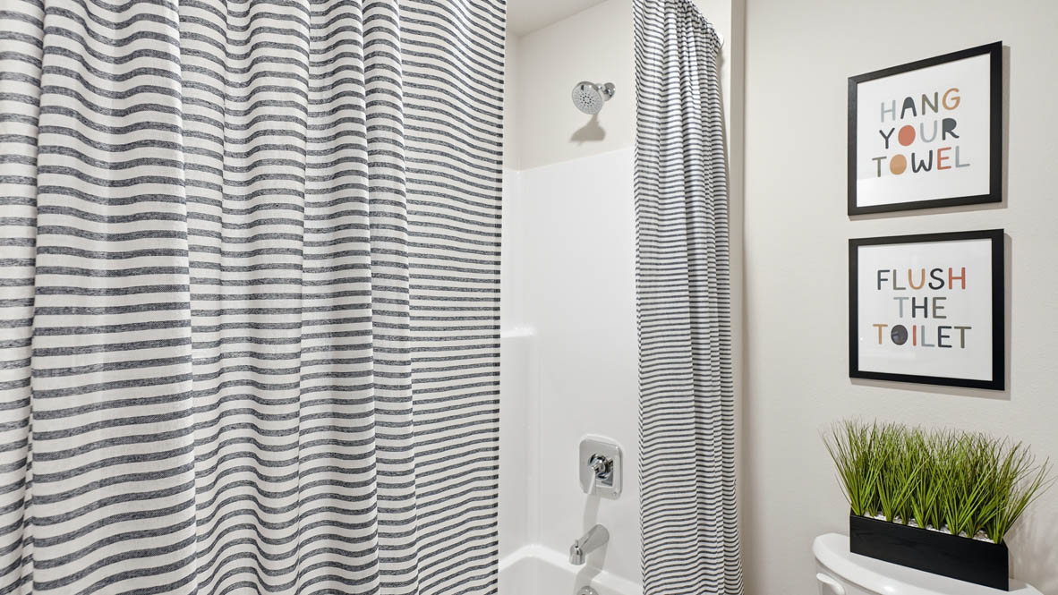 Stevens Ranch secondary bathroom with vanity with shaker style dark stained cabinets and white quarts countertops with toilet closet and tub shower