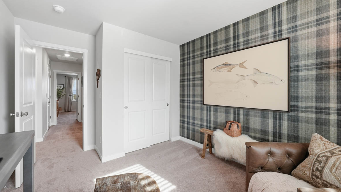 Stevens Ranch bedroom mock office with a desk, hung up shelves, a couch, chair, and a painting