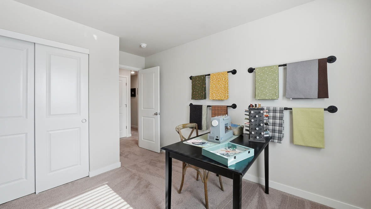 Stevens Ranch bedroom mock office with a desk, hung up shelves, a couch, chair, and a painting