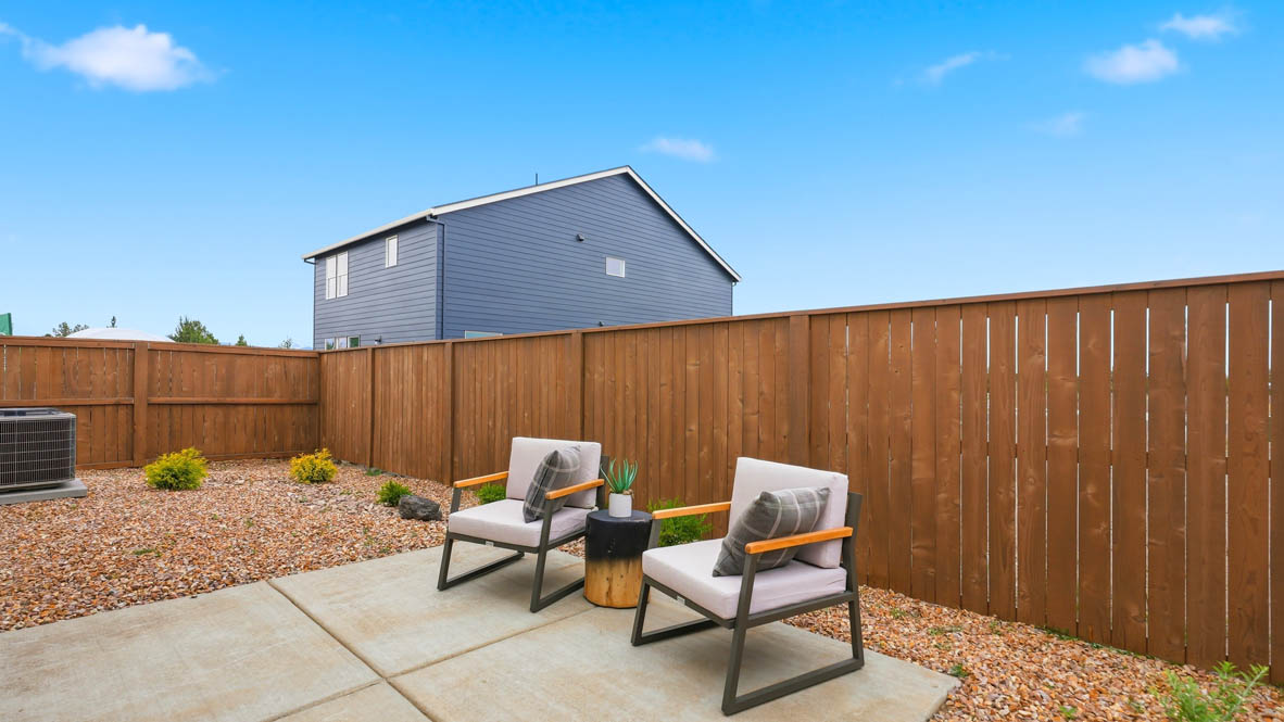 Stevens Ranch backyard with paved concrete section staged with outdoor furniture and desert rock landscaping