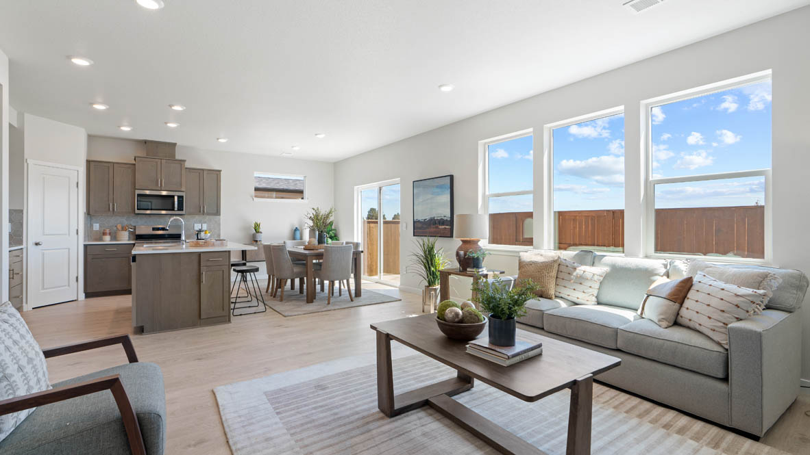 Stevens Ranch Great room with carpet, coffee table, couch, windows, plants, laminate flooring, and the kitchen in the background