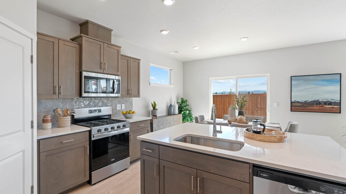 Stevens Ranch kitchen with laminate flooring, island with a sink, quartz countertops, stainless steel appliances, slide in glass door