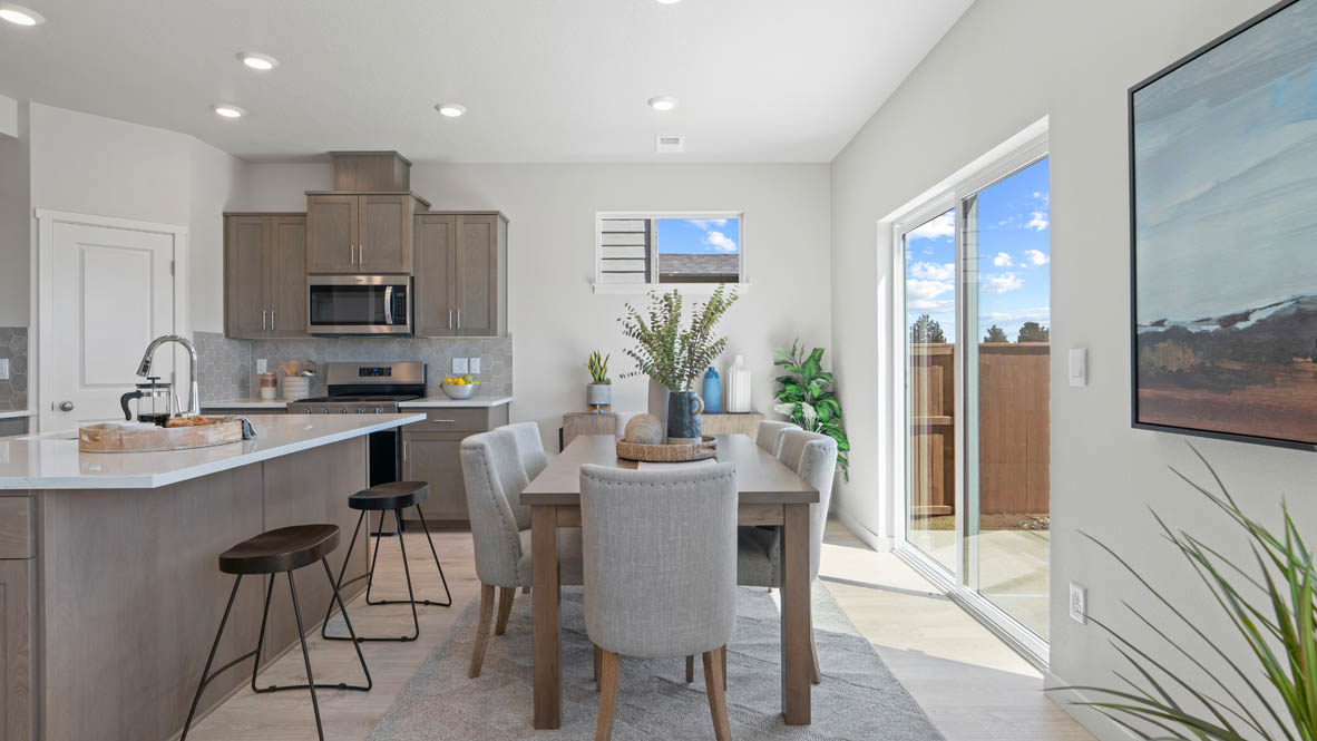 Stevens Ranch dining room with table, four chairs, windows, painting, laminate flooring, with the kitchen island.