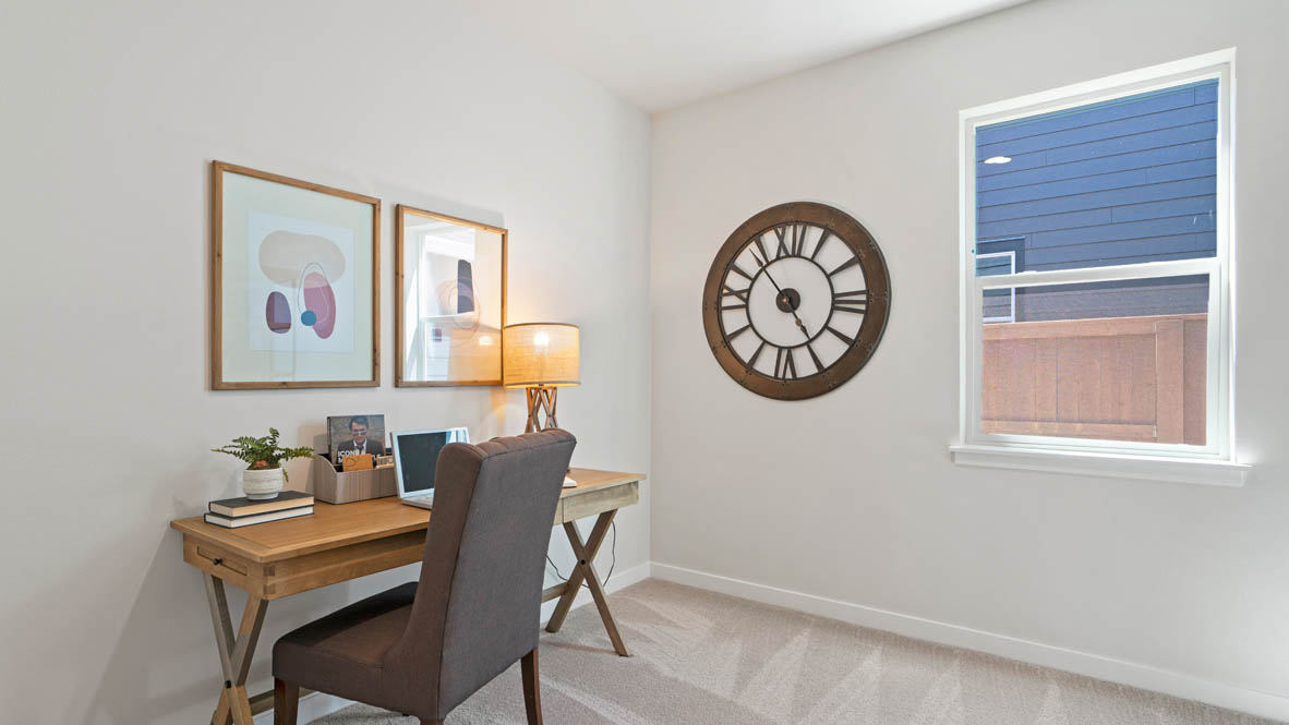 Stevens Ranch den with a single chair, table desk, lamp, big clock, window, and paintings