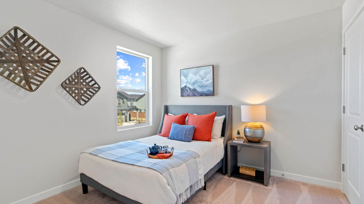 Stevens Ranch bedroom with blankets, nightstand with lamp, dresser, and paintings