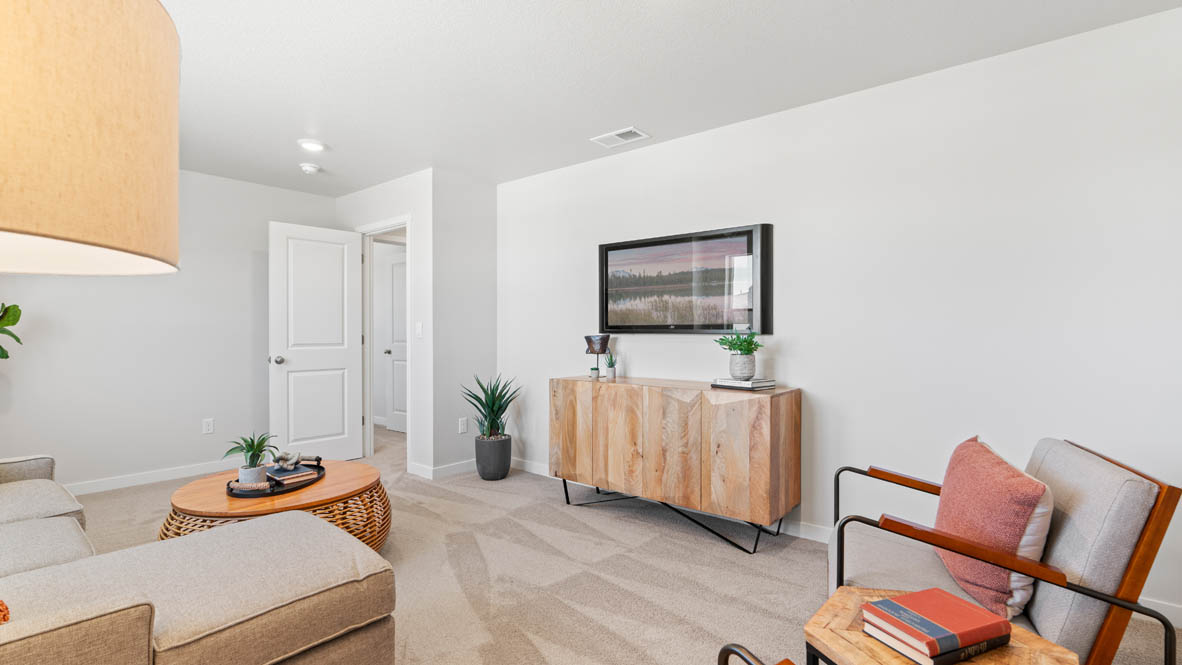 Stevens Ranch bonus room with sectional couch, coffee table, lamp, two chairs with a center piece, entertainment center, and two paintings