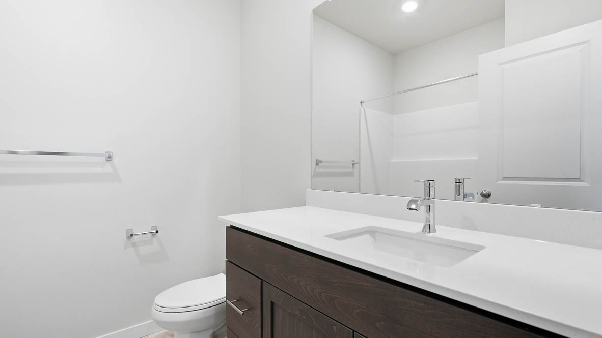 Stevens Ranch bathroom with vanity, mirror, toilet, and dark stained cabinets