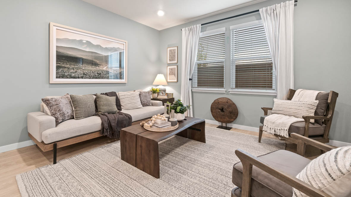 Stevens Ranch Great Room with carpet, laminate flooring, two brown chairs, a white couch, a painting, a decorative wood piece, a lamp, windows with blinds, a coffee table