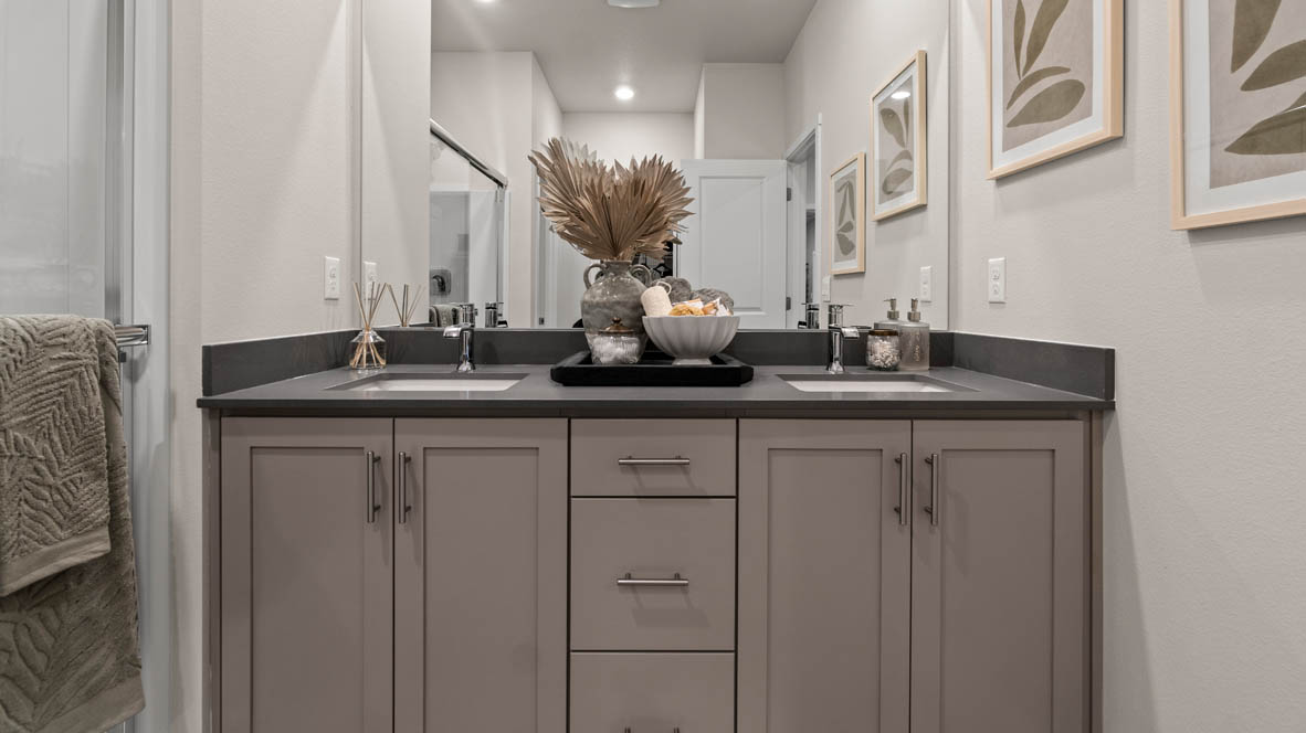Stevens Ranch primary bathroom with laminate flooring, grey cabinets, quartz countertops, double vanity, walk-in shower with sliding glass door