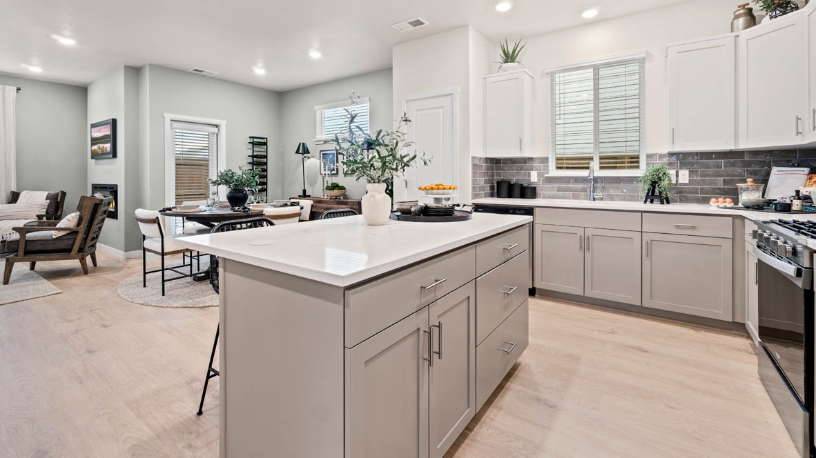 Stevens Ranch Kitchen with quartz countertops, gray cabinets, laminate flooring, stainless steel appliances, plant, and view of dining room