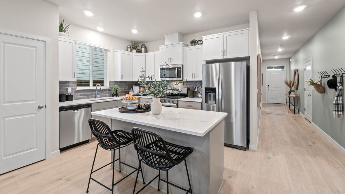 Stevens Ranch Kitchen with quartz countertops, gray cabinets, laminate flooring, stainless steel appliances, plant, and view of hallway