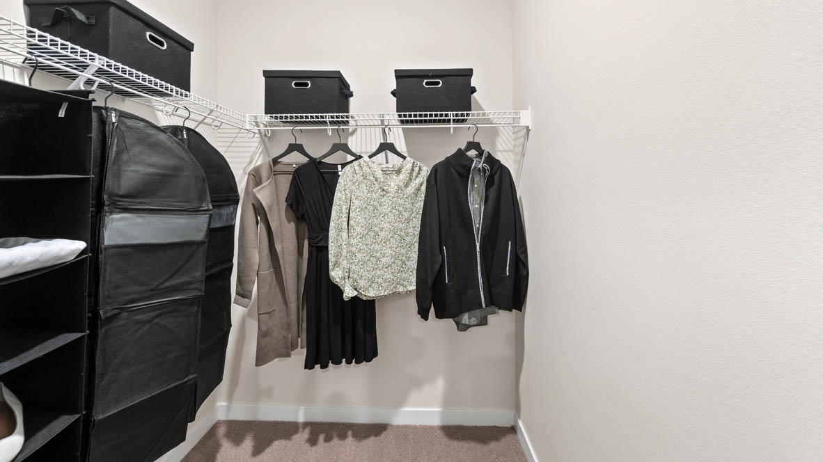 Stevens Ranch walk in closet, with white wire shelving, hanging clothes, organizers, and white walls
