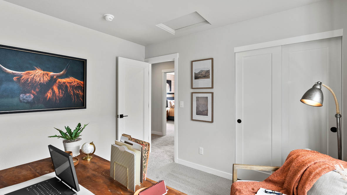 Stevens Ranch Diamond 3816 bedroom mock office with a desk, hung up shelves, a couch, chair, and a painting