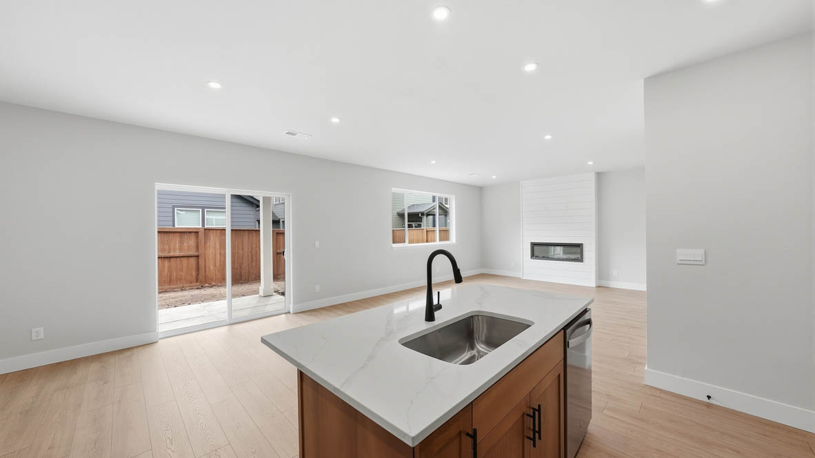 Stevens Ranch kitchen with wood cabinets, sink, solid surface countertops, and island