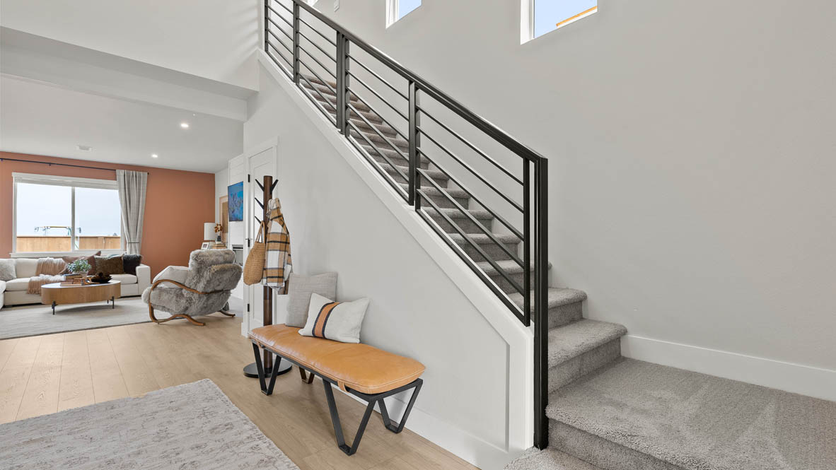 Stevens Ranch entry with black banister, carpeted stairs, bench, tan flooring
