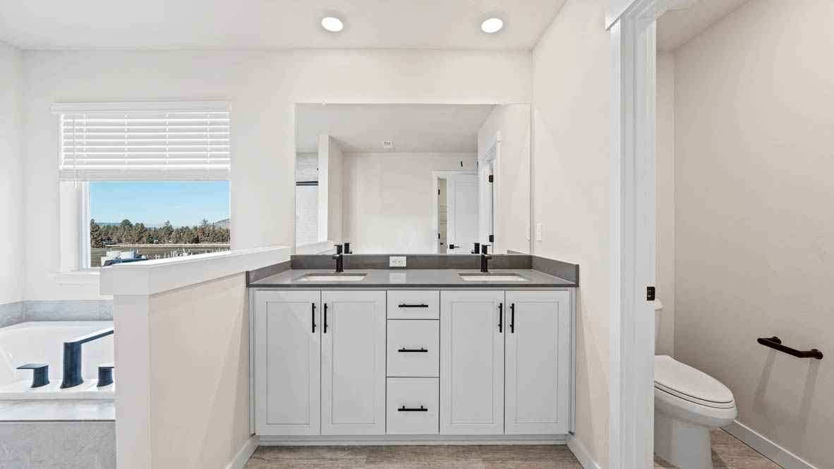 Stevens Ranch prmiary bathroom with double vanity, mirror, quartz countertops, and bathtub