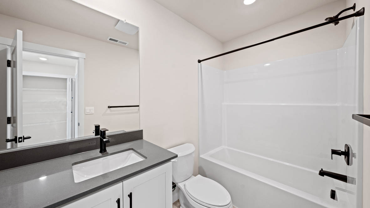 Stevens Ranch bathroom with quartz countertops and mirror, toilet, and shower tub