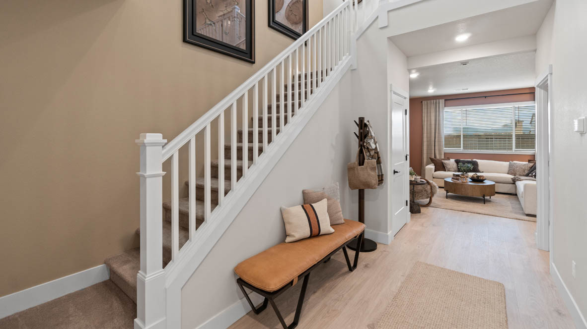 Stevens Ranch Entry with accent wall painted on stairs, laminate flooring, staircase with white railing, entry bench