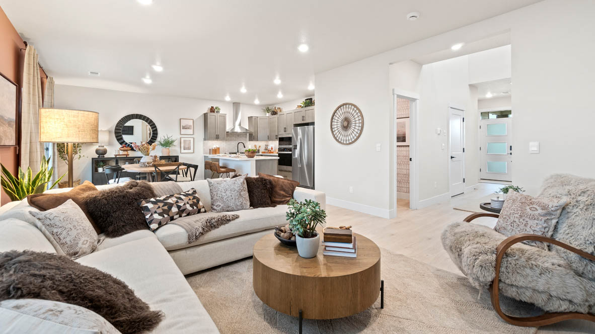 Stevens Ranch great room with L shaped sectional couch, carpeting, and center coffee table as well as window drapes, fireplace on a shiplap wall, and a fuzzy corner chair