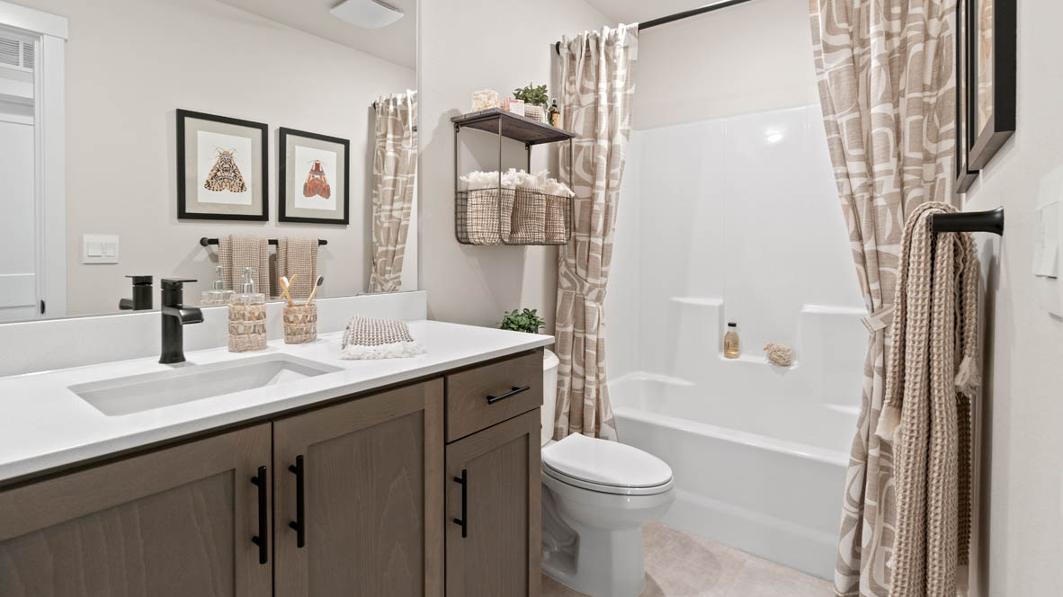 Stevens Ranch secondary bathroom with single sink vanity, dark shaker style cabinets, and tub shower with curtains