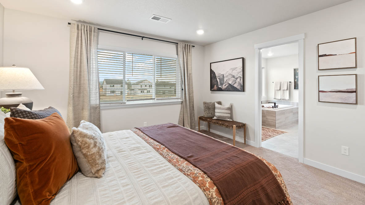 Stevens Ranch Primary bedroom with carpeting, wall paper, a dark wood dresser on either side of the bed, three windows, and burnt orange accent pieces.
