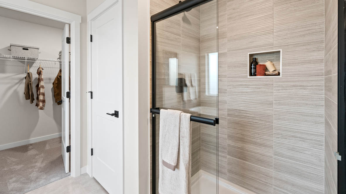Stevens Ranch Primary bathroom with dark stained cabinetry, two sink vanity, bathtub, walk in closet, and shower