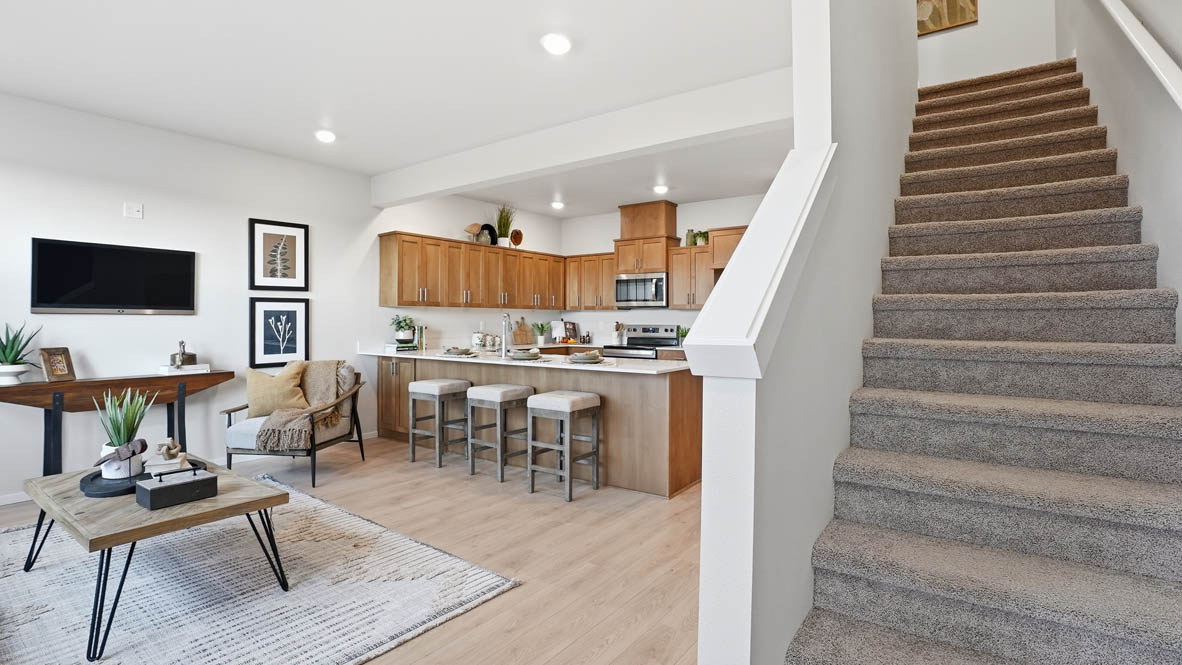 Stevens Ranch Townhomes entry with carpeted stairs, banister, laminate flooring, and the great room and dining room in the background