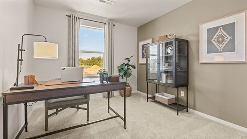 Monrovia Den set up as an office with a desk, media cabinet, and plants