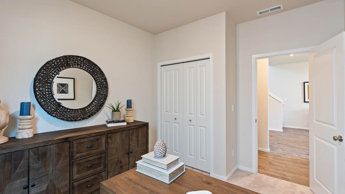 Monrovia bedroom with a desk, chair, window, dresser, round mirror, and painting