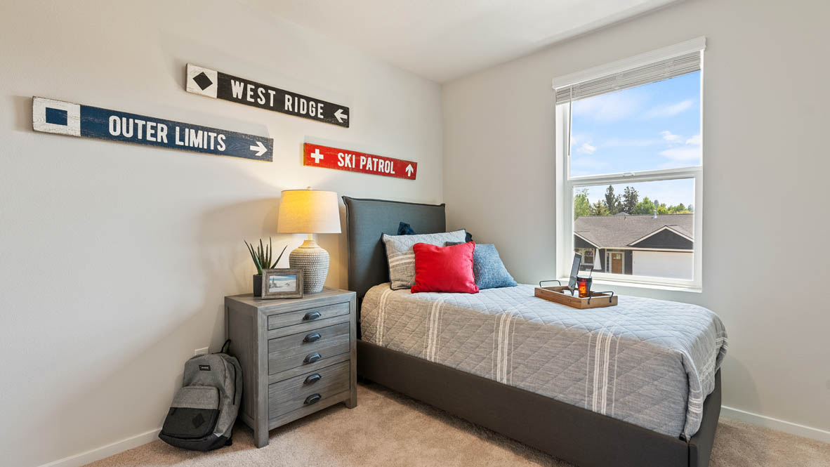 Monrovia bedroom with a bed and red accent pillow, a nightstandand lamp, and window