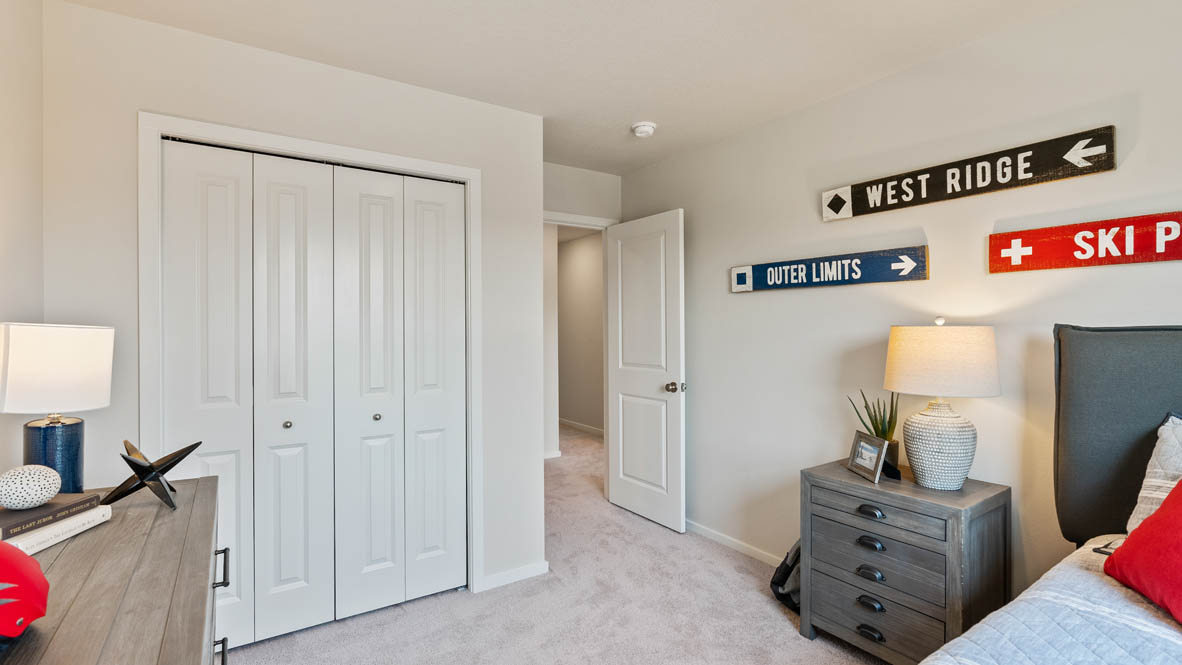 Monrovia bedroom with a bed and red accent pillow, a nightstand and lamp, and closet