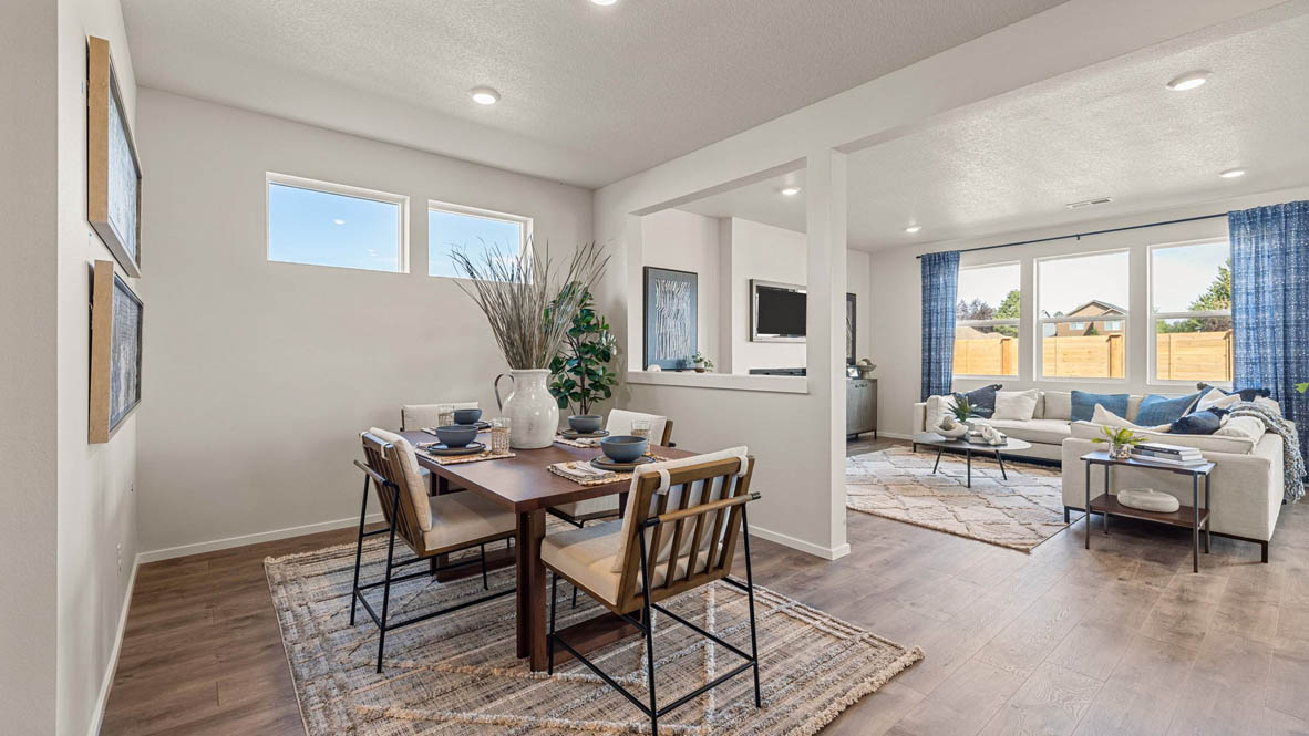 Monrovia Dining room with four chairs set at the table placed over an area rug and connected to the great room with open barrier wall