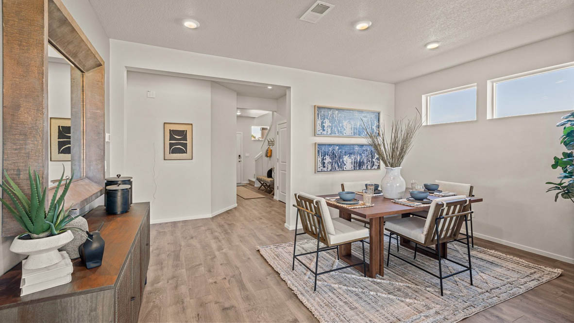 Monrovia Dining room with four chairs set at the table and an area rug underneath. To the left there is a mirror over a console against the wall