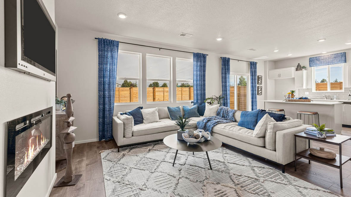 Monrovia Great room with L shaped sectional couch facing the fireplace and TV over an area rug with a coffee table and chair in the corner