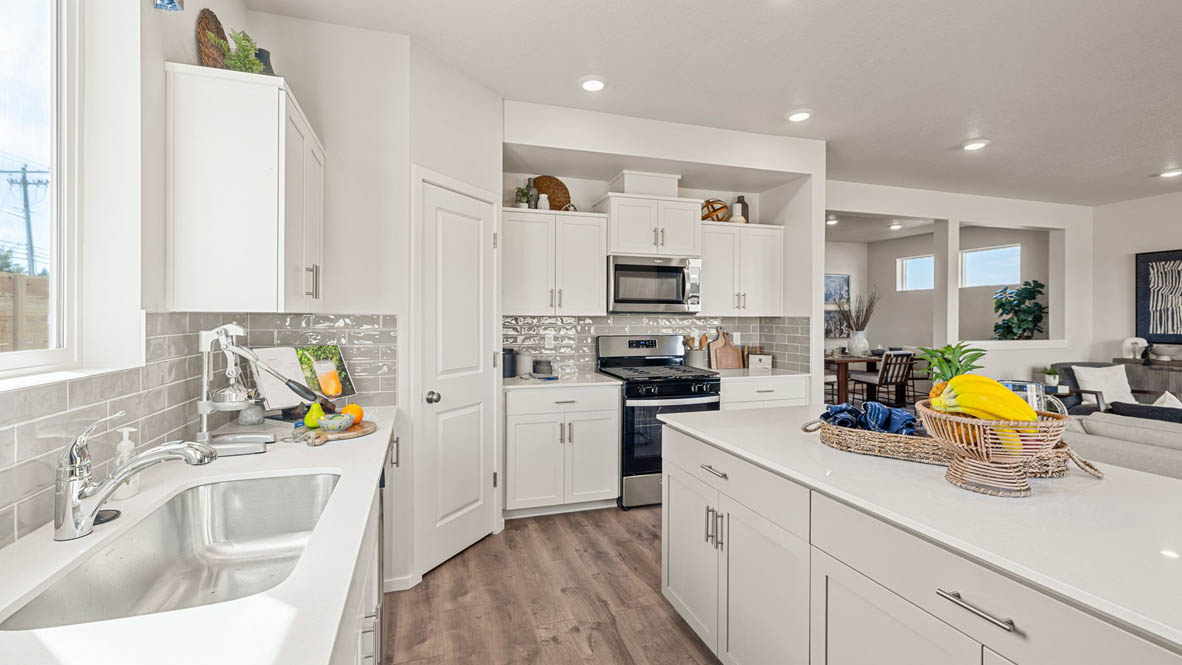 Monrovia Kitchen with island that has white quartz countertops, two seats set up at the island, stainless steel appliances, a sliding glass door to the backyard, and white shaker style cabinets