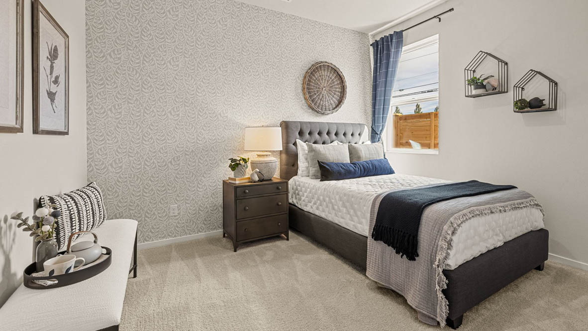 Monrovia Bedroom with gray patterned wallpaper, a gray and white bed, a bench against the left wall, and bedroom decor