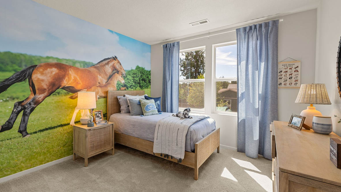 Monrovia Bedroom with horse theme, blue bedding and window drapes, large horses on the wallpaper, light wood furniture, and carpeting