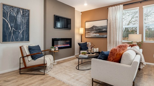 Lowrie Estates great room with couch and accent wall with fire place and area rug and an orange accent wall on the window side
