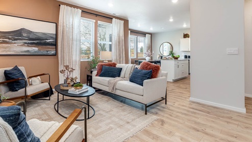 Lowrie Estates great room with white couch, area rug, coffee table, and two chairs next to fireplace accent wall