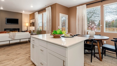 Lowrie Estates kitchen with white quartz countertops, stainless steel appliances, a kitchen island, and white shaker style cabinets next to the dining room