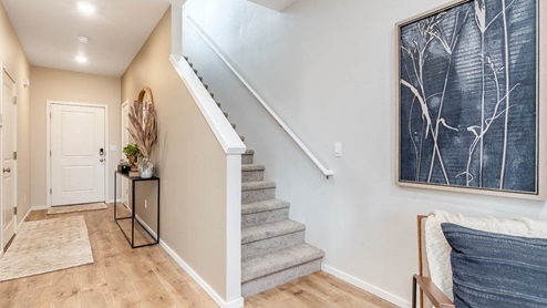 Lowrie Estates carpeted stairs going up with entry art and view of the front door and laminate floors