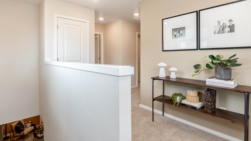 Lowrie Estates upstairs hallway landing with carpeting and a long table under wall art