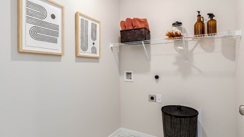 Lowrie Estates laundry room with white wire shelving and wall art