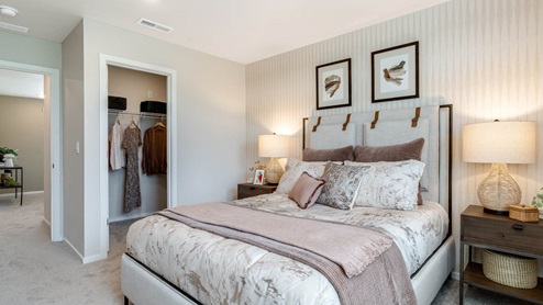 Lowrie Estates Primary bedroom with king bed and carpeting flooring with two accent tables and drapes on the windows